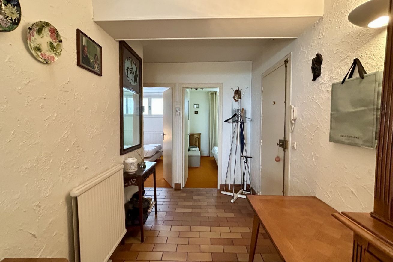 A hallway with a radiator, a wooden bench, a door, and a wall-mounted picture frame.