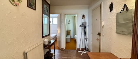 Un couloir avec un radiateur, un banc en bois, une porte et un cadre photo fixé au mur.