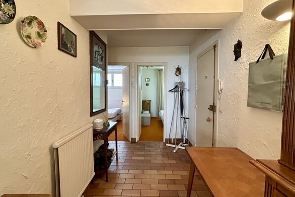 A hallway with a radiator, a wooden bench, a door, and a wall-mounted picture frame.