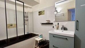 Een badkamer met een bad, toilet, wastafel en spiegel.