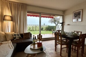 Una sala de estar con un sofá, una mesa de centro y una mesa de comedor preparada para cuatro personas.