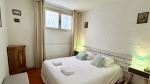 Een net opgemaakt bed met kussens en een nachtkastje met een lamp.