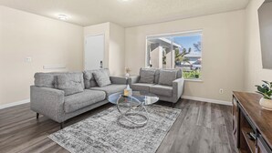 A modern living room with two grey sofas, a glass coffee table, and a wooden floor. - Peaceful and Quiet 4 Br house with Garage (Sacramento)