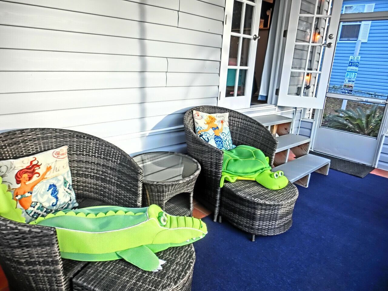 A patio with wicker furniture, a green crocodile plush toy, and a bench.