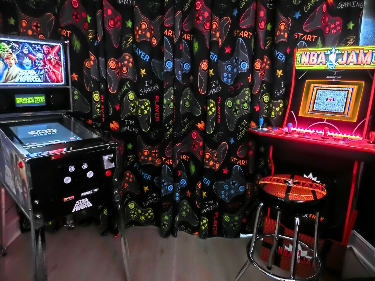 Una sala de juegos con taburetes tipo arcade, una consola de videojuegos y un fondo temático de Star Wars.