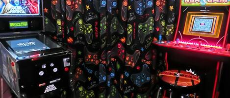 Una sala de juegos con taburetes tipo arcade, una consola de videojuegos y un fondo temático de Star Wars.