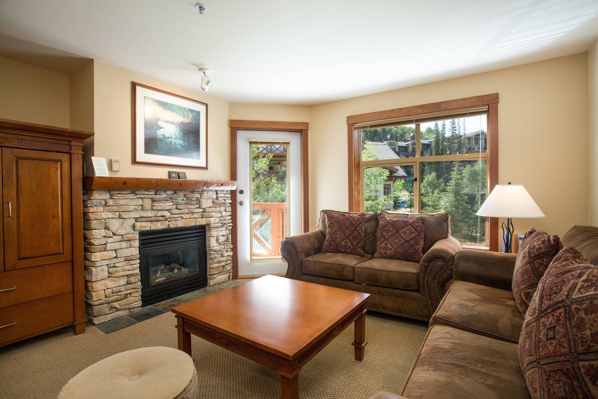 A living room with a stone fireplace, a sofa, a coffee table, and a lamp.