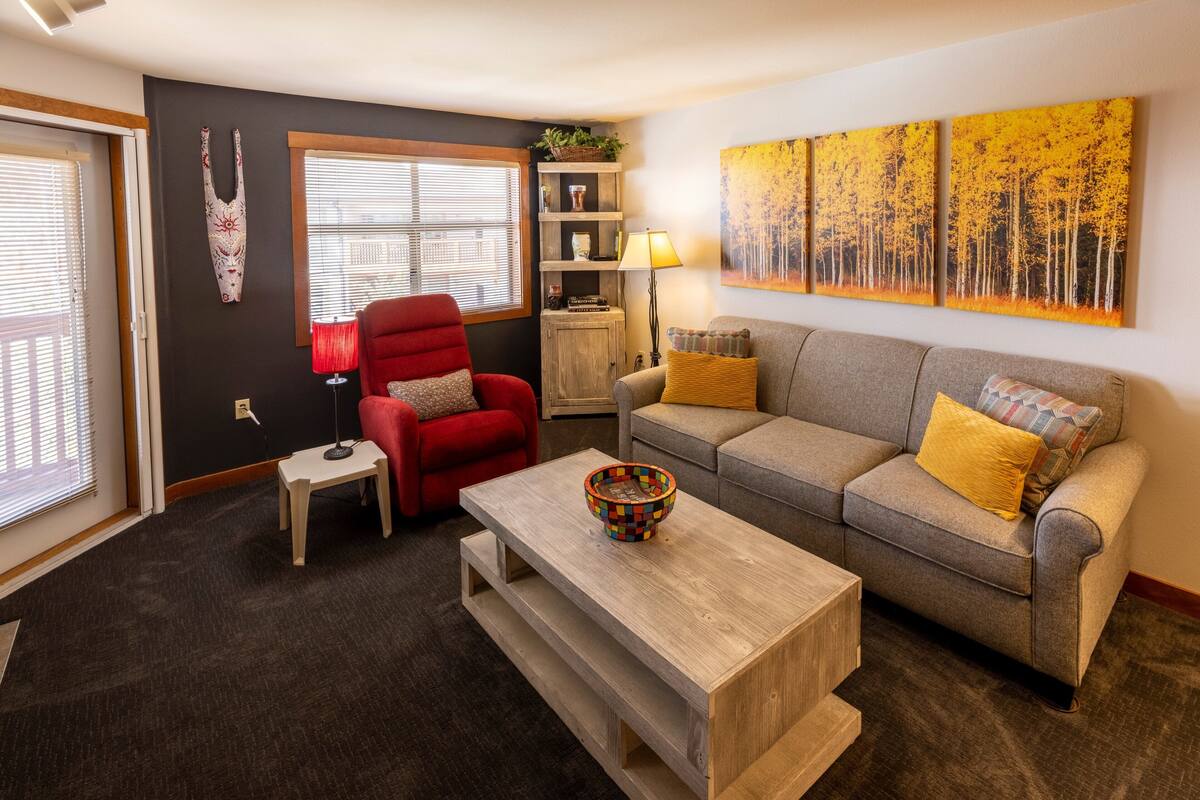 A living room with a grey sofa, red armchair, and a wooden coffee table.