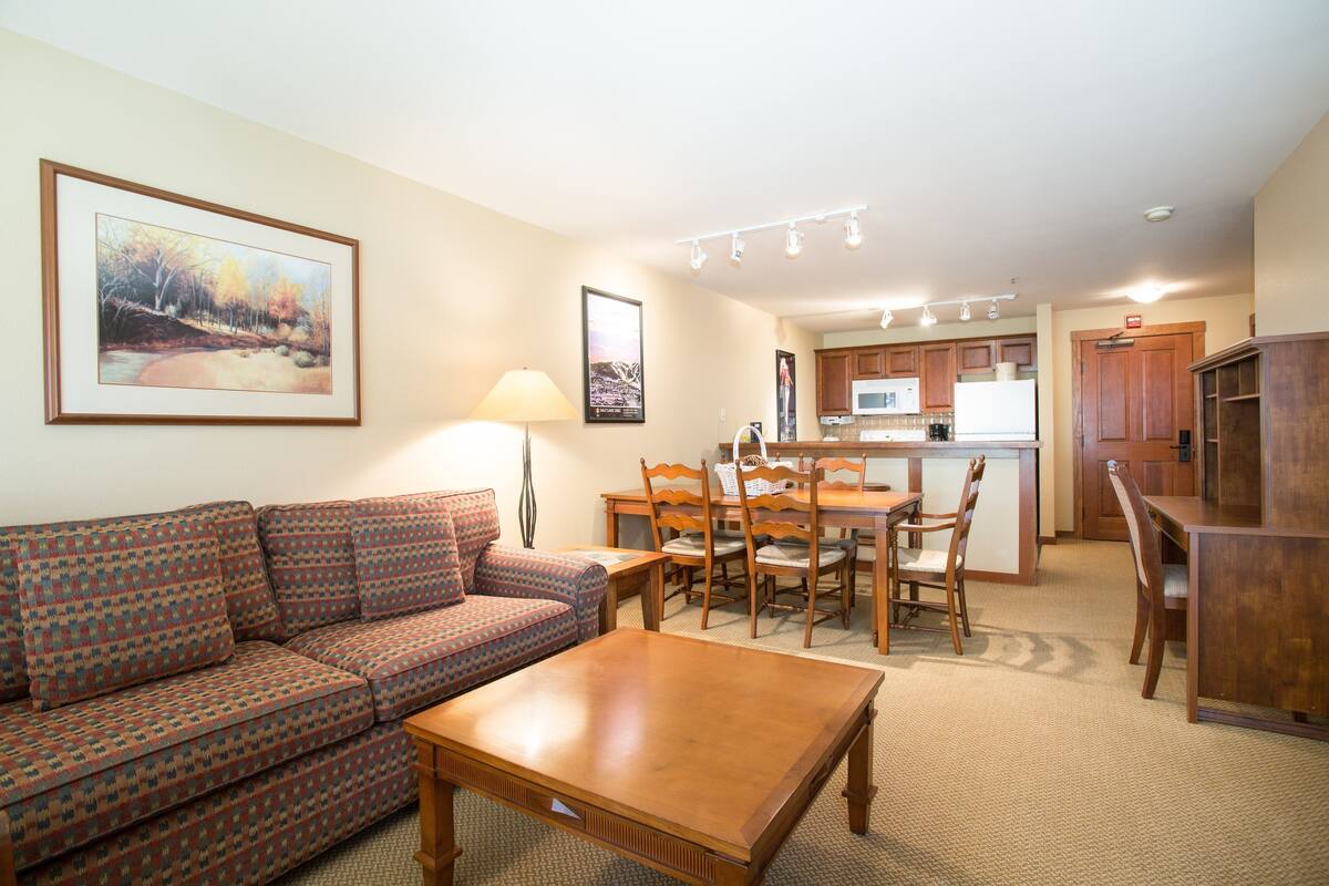 A living room with a sofa, a wooden coffee table, and a dining area with a table and chairs.