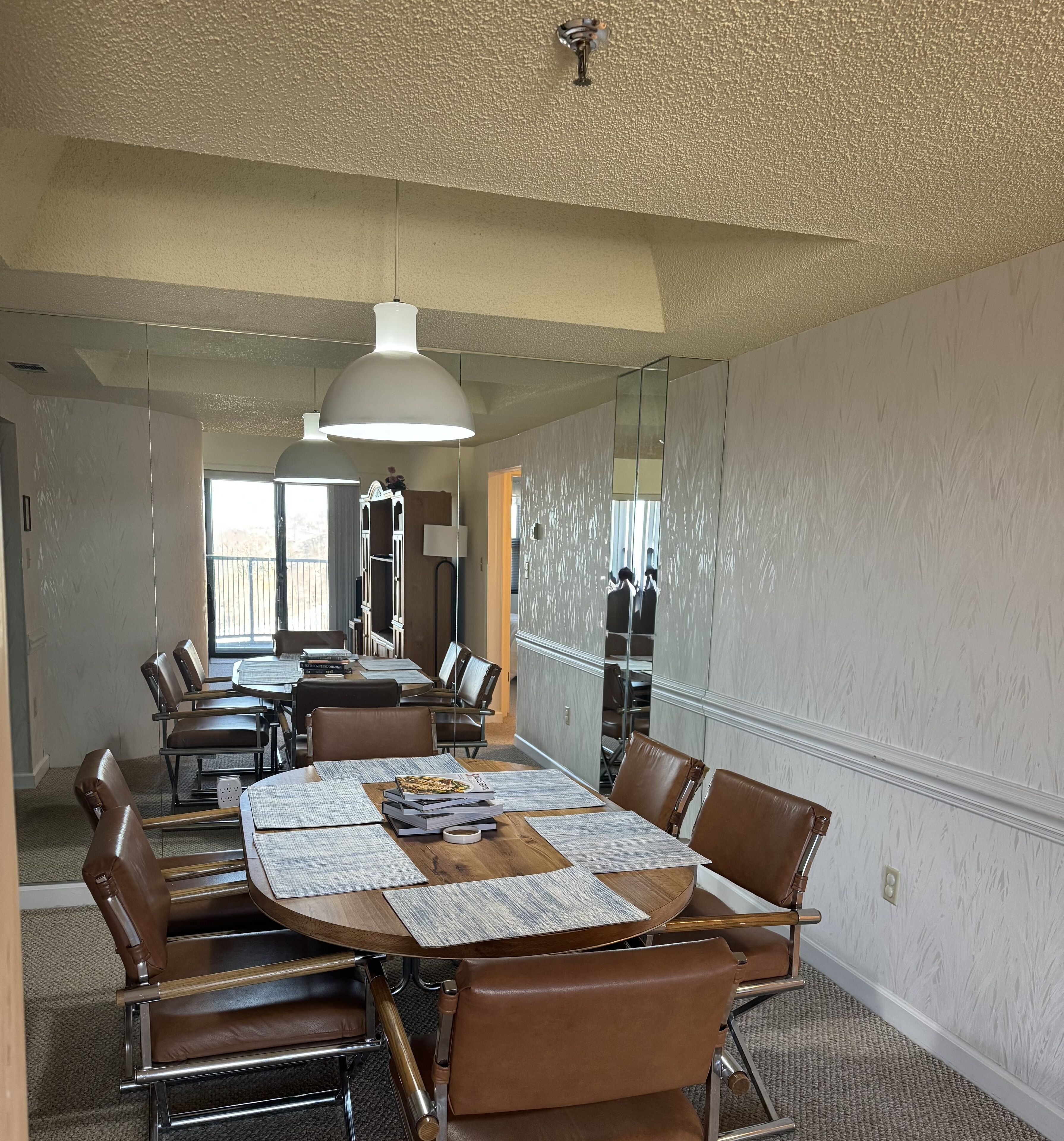 Une salle de conférence avec une table ronde, des fauteuils en cuir et un grand miroir.