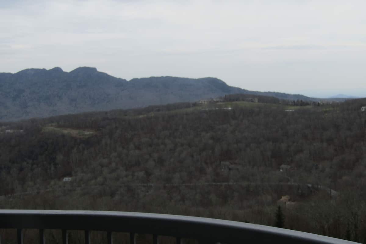 A mountainous landscape with a view of a house in the distance.