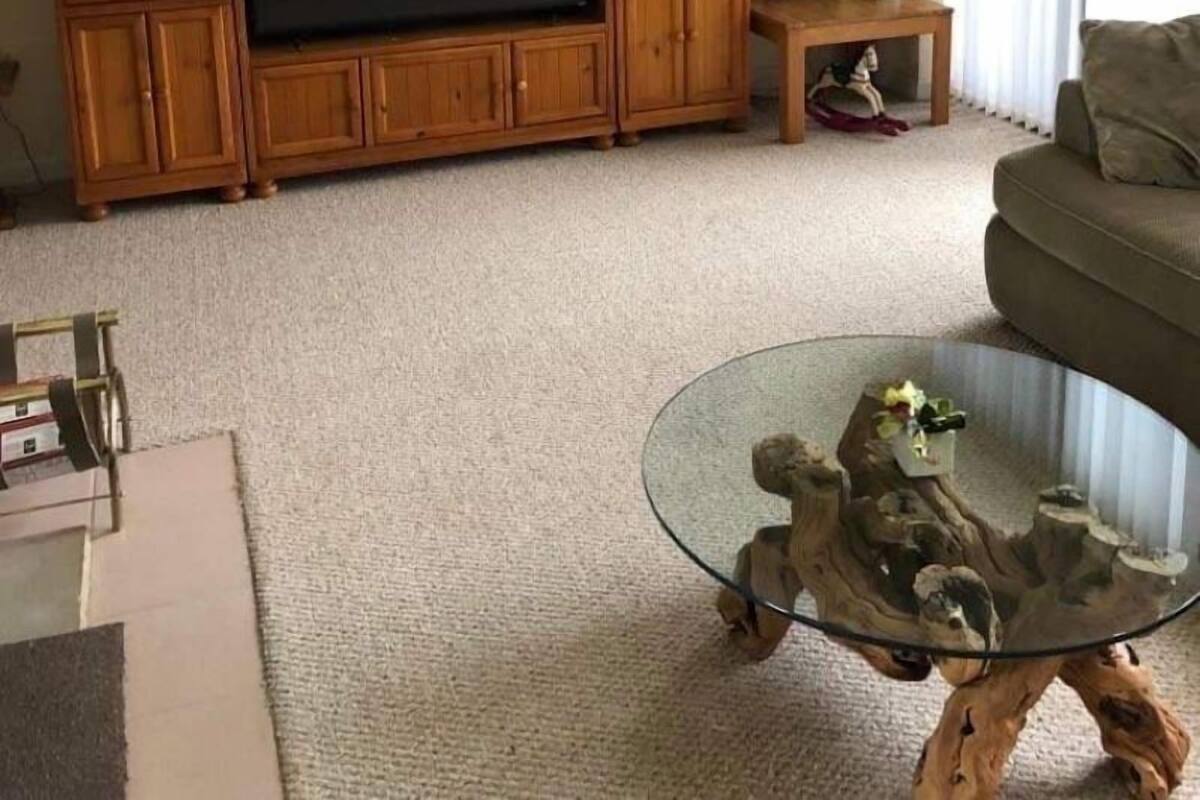 A living room with a wooden entertainment center, a glass coffee table, and a sofa.