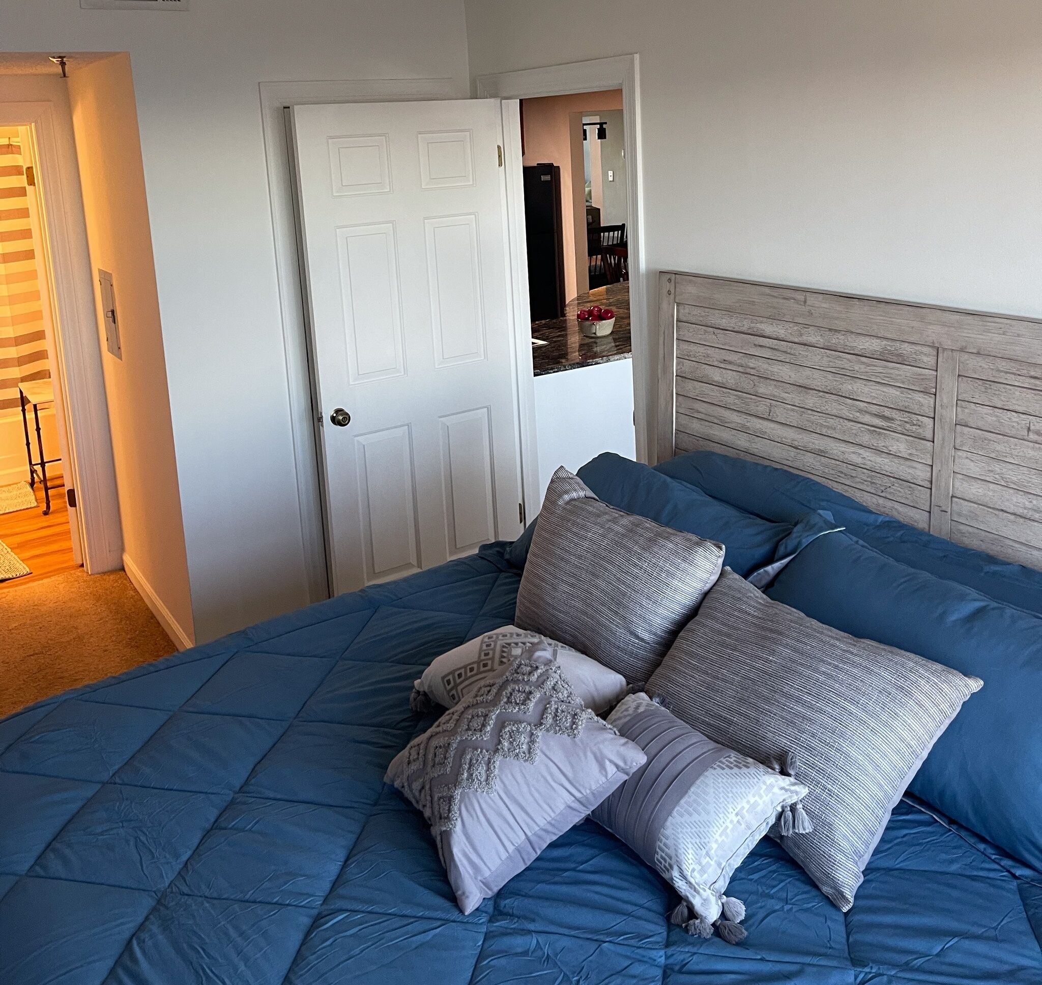 A bedroom with a large bed, a wooden headboard, and a white door.