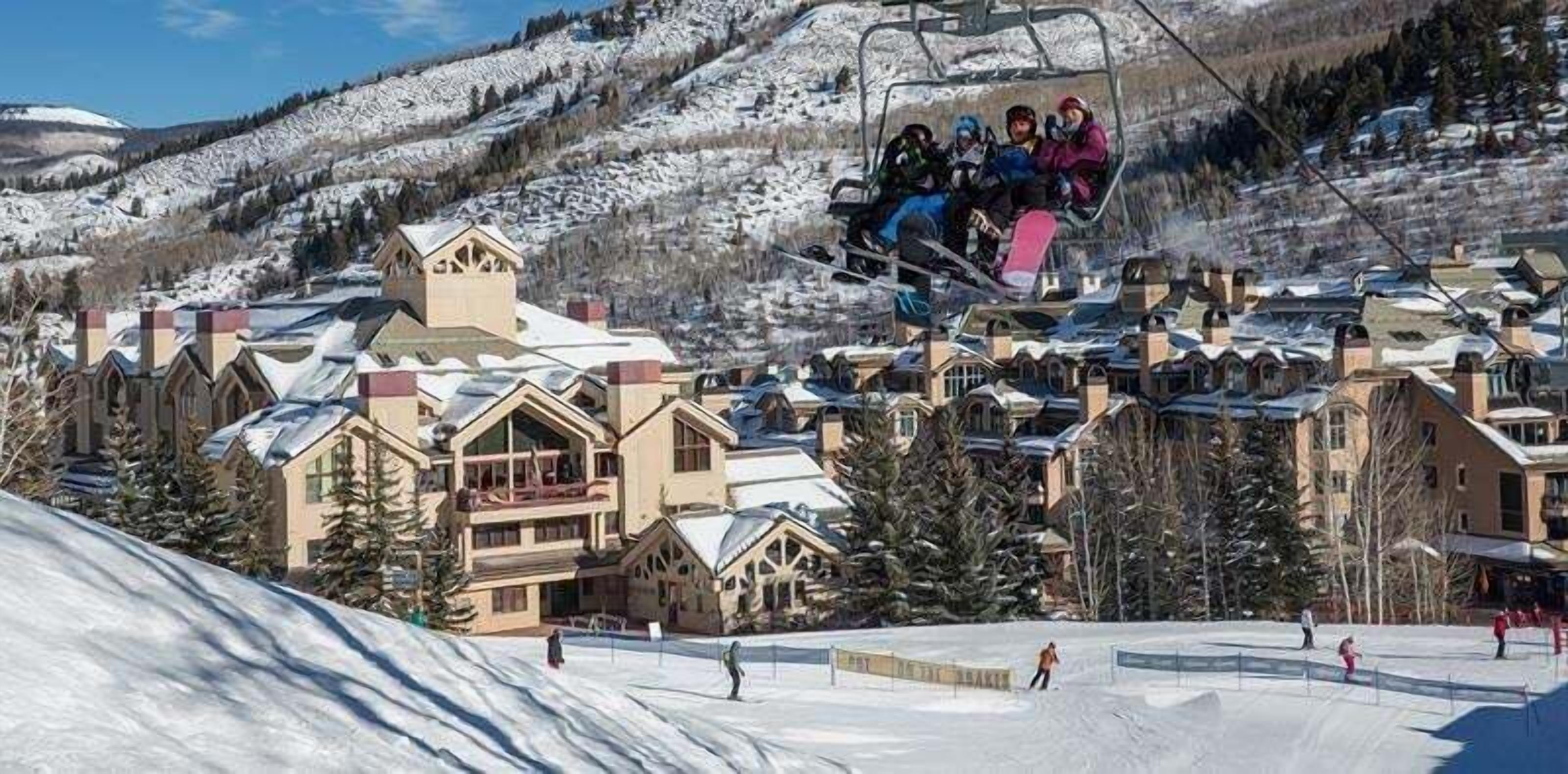 A ski resort with a chairlift, snow-covered buildings, and a ski slope.