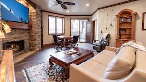 A spacious living room with a stone fireplace, a large flat-screen TV, a ceiling fan, and a comfortable sofa. - Beaver Creek Resort CO - Townsend Place & Strawberry Park Condos (Avon)