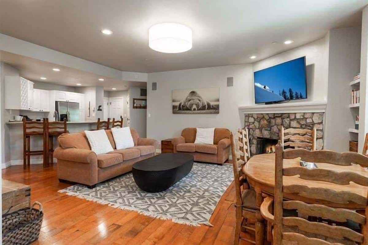 Ein geräumiger Wohnbereich mit Kamin, zwei Sofas, einem Couchtisch und einem Esstisch mit Stühlen.