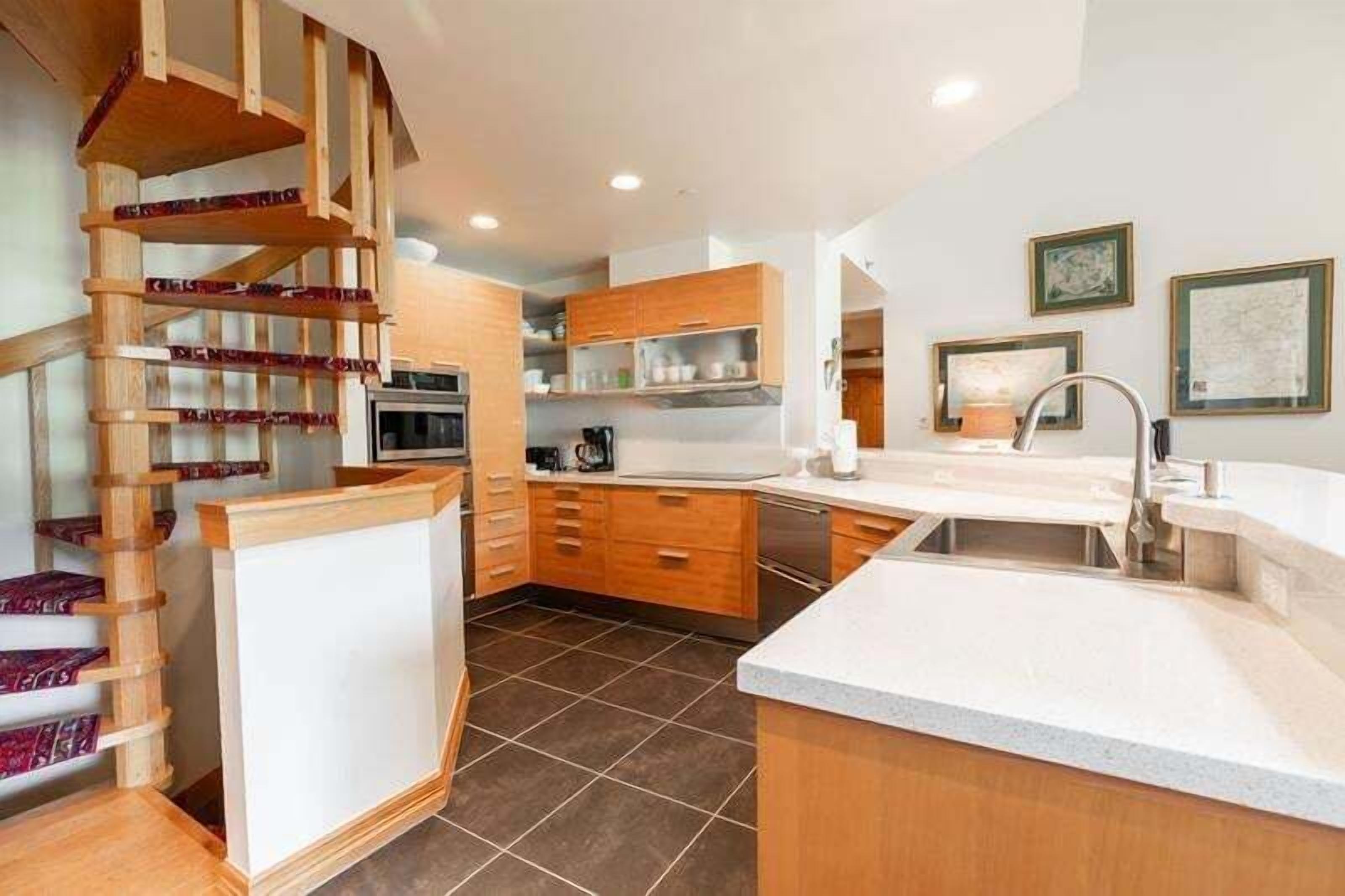 A modern kitchen with wooden cabinets, a built-in stove, and a large island with a sink.