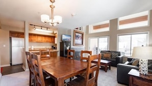 A spacious living area with a wooden dining table, a sofa, and a TV. - Convenient Condos - Vail Ski Resort CO (Vail)