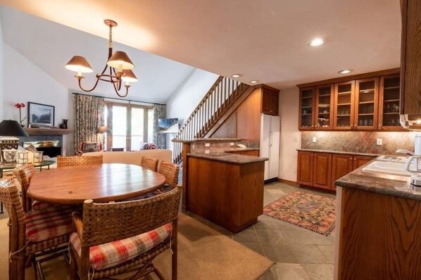 Una cocina amplia con armarios de madera, una isla central y un comedor con sillas de mimbre.