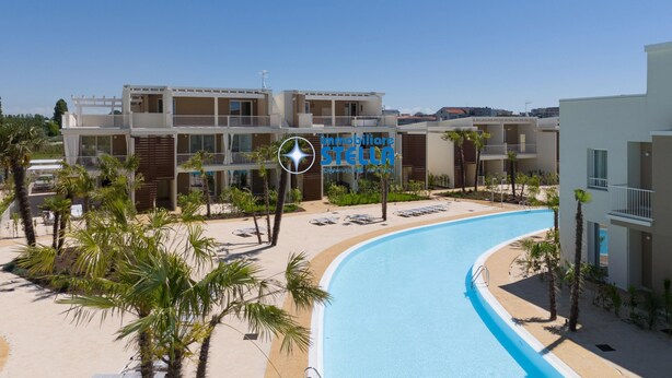 A resort with a swimming pool, multiple balconies, and palm trees. - *Wave Island Resort F3* [ pool & free park ] (Lido di Jesolo)