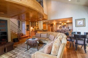 A spacious living area with a large sectional sofa, a dining table with chairs, a staircase, and a kitchen in the background. - Vail Ski Resort Northwoods Condos (Vail)