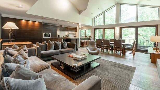 A spacious living area with a modern sofa set, a coffee table, and a dining area with chairs and a table. - Vail Ski Resort Northwoods Condos (Vail)