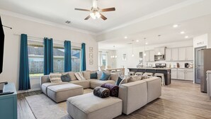 Una sala de estar amplia con un sofá modular, un comedor y una cocina.