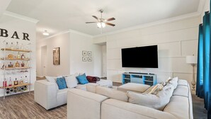 Una sala moderna con un sofá modular, un televisor montado y un ventilador de techo.