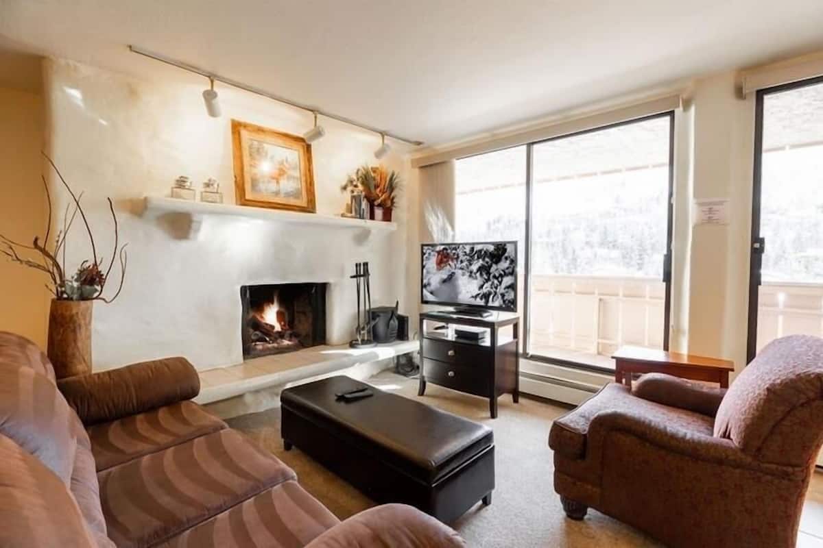 Een woonkamer met een open haard, een televisie en een bank.