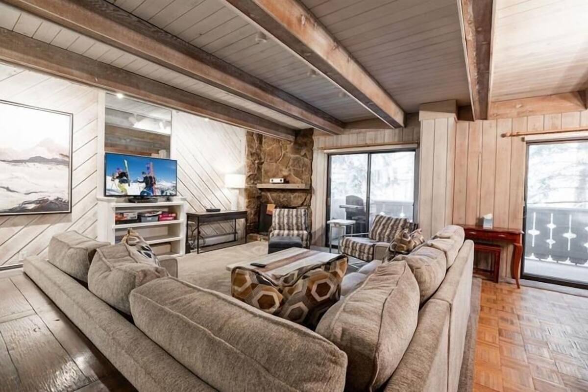Een gezellige woonkamer met een ruime hoekbank, een open haard en een televisie.