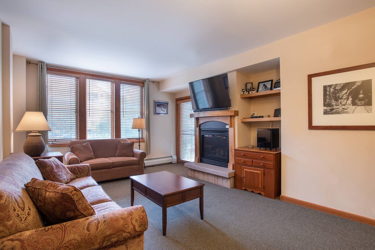 Una sala de estar con chimenea, televisor y sofá.
