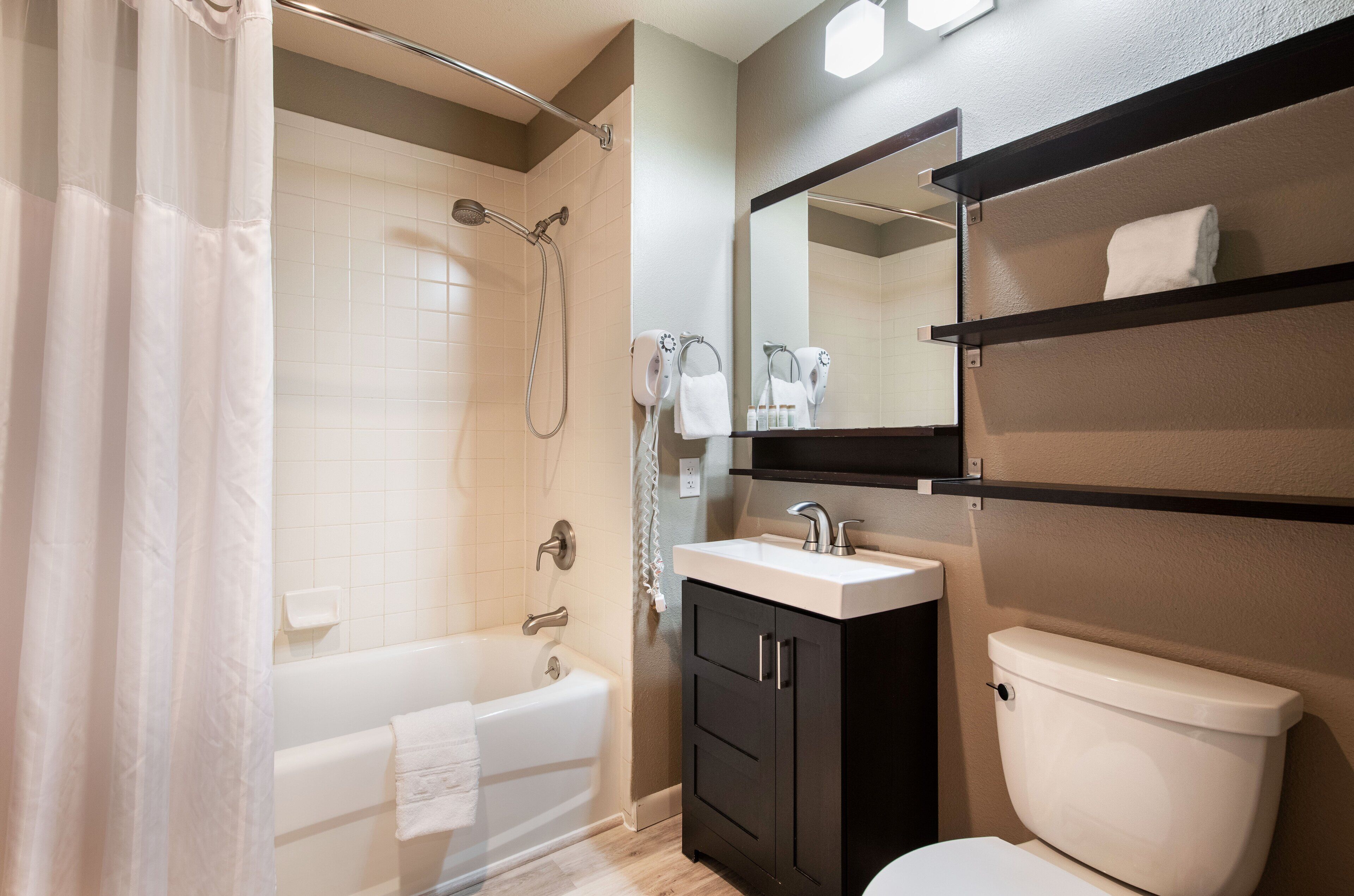 Ein modernes Badezimmer mit Badewanne, Toilette, Waschbecken und Dusche.