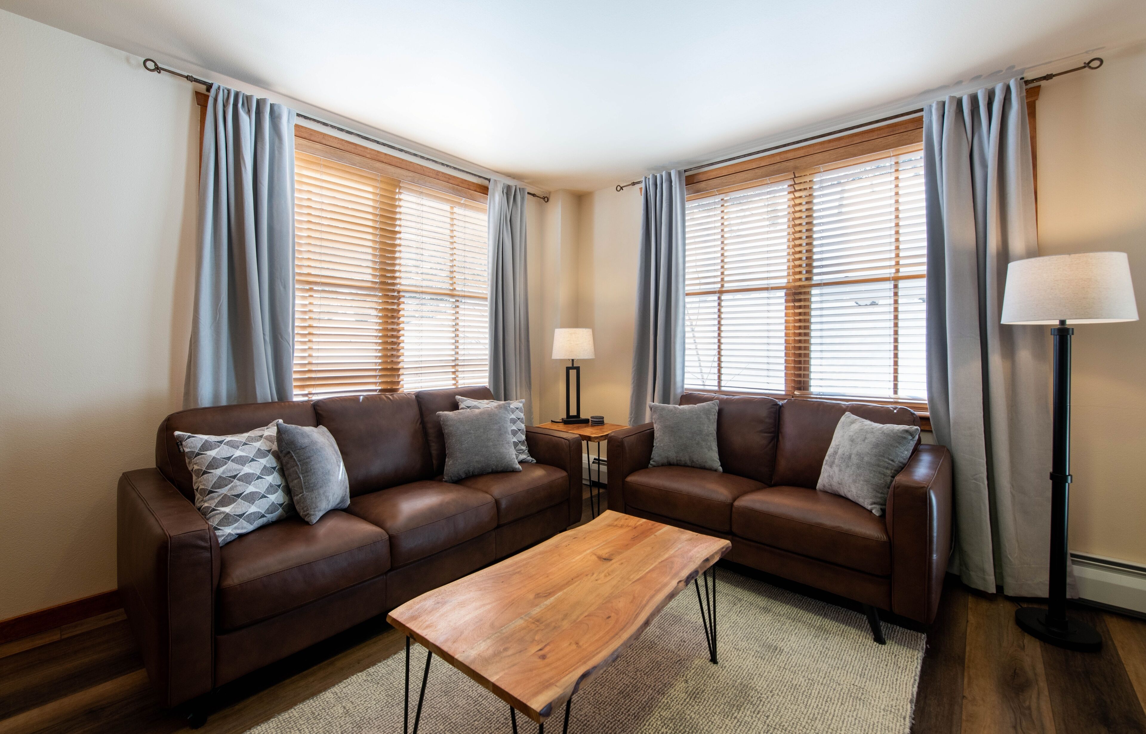 A living room with two brown leather sofas, a wooden coffee table, and a floor lamp.