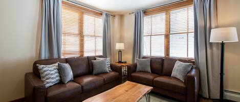 A living room with two brown leather sofas, a wooden coffee table, and a floor lamp.