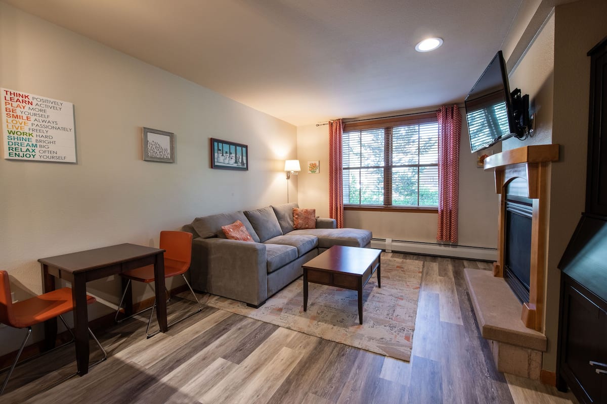 A living room with a sofa, coffee table, and a TV mounted on the wall.