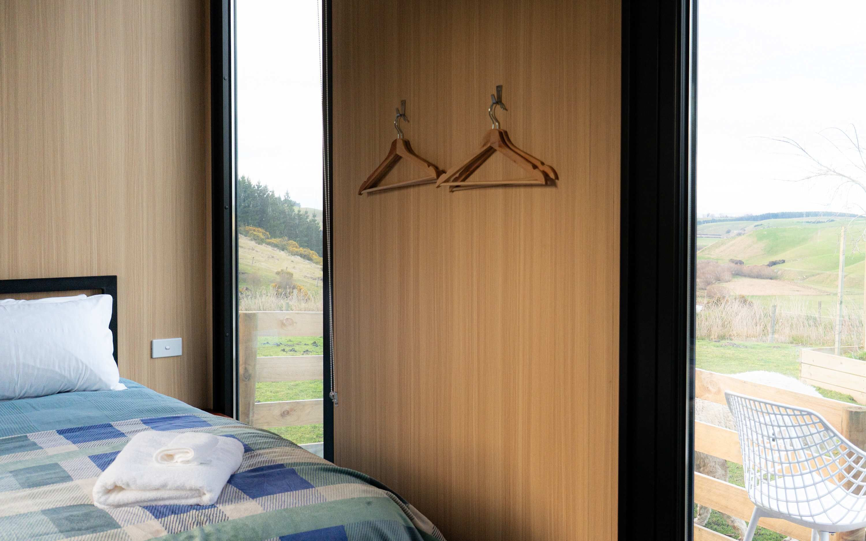 Ein Schlafzimmer mit einem Bett, einer Holztür und Blick auf eine ländliche Landschaft.