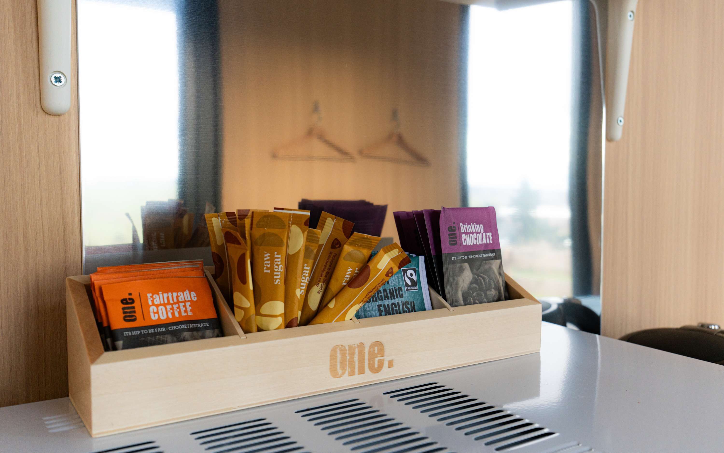 Une boîte en bois contenant divers produits issus du commerce équitable, notamment du café et du chocolat.