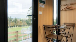 Ein Zimmer mit Holztisch und Stühlen, Blick auf eine Wiese und ein Schild, das WLAN für Gäste anzeigt.