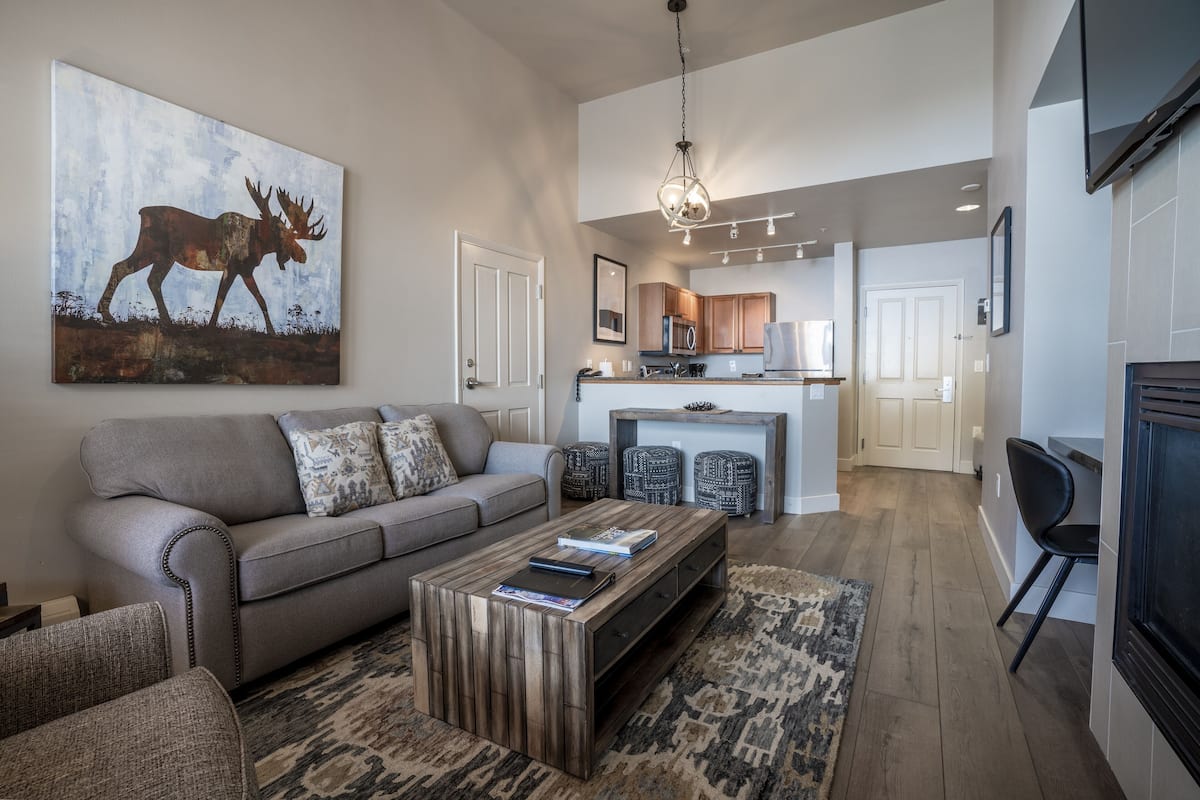 A modern living room with a sofa, coffee table, and a painting of a moose.