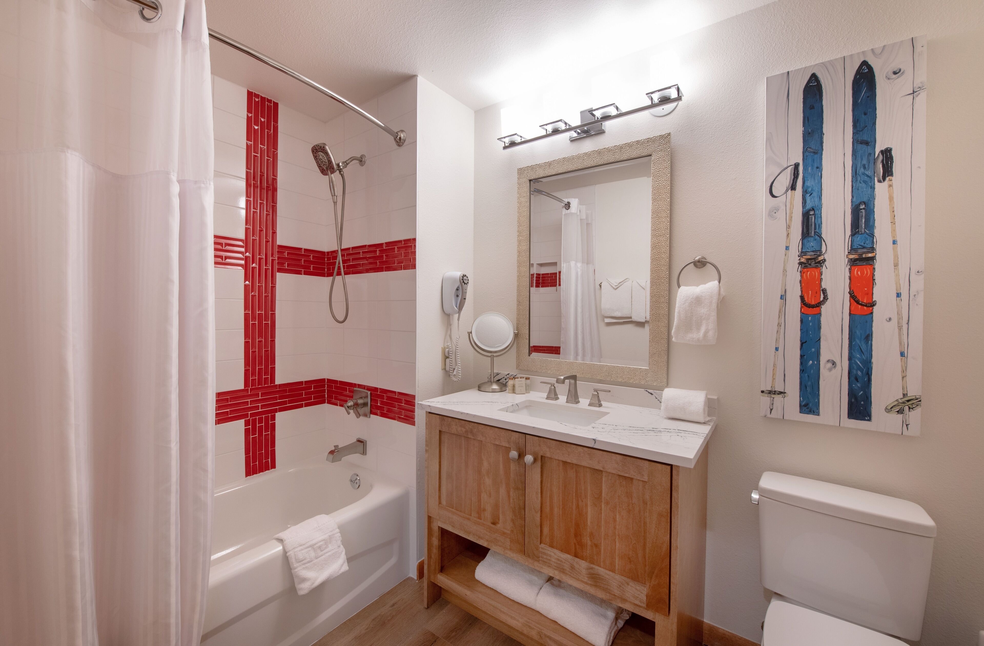 A bathroom with a shower, bathtub, wooden vanity, and a large mirror.
