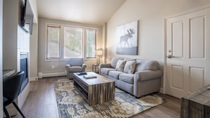 A living room with a sofa, coffee table, and a TV mounted on the wall.