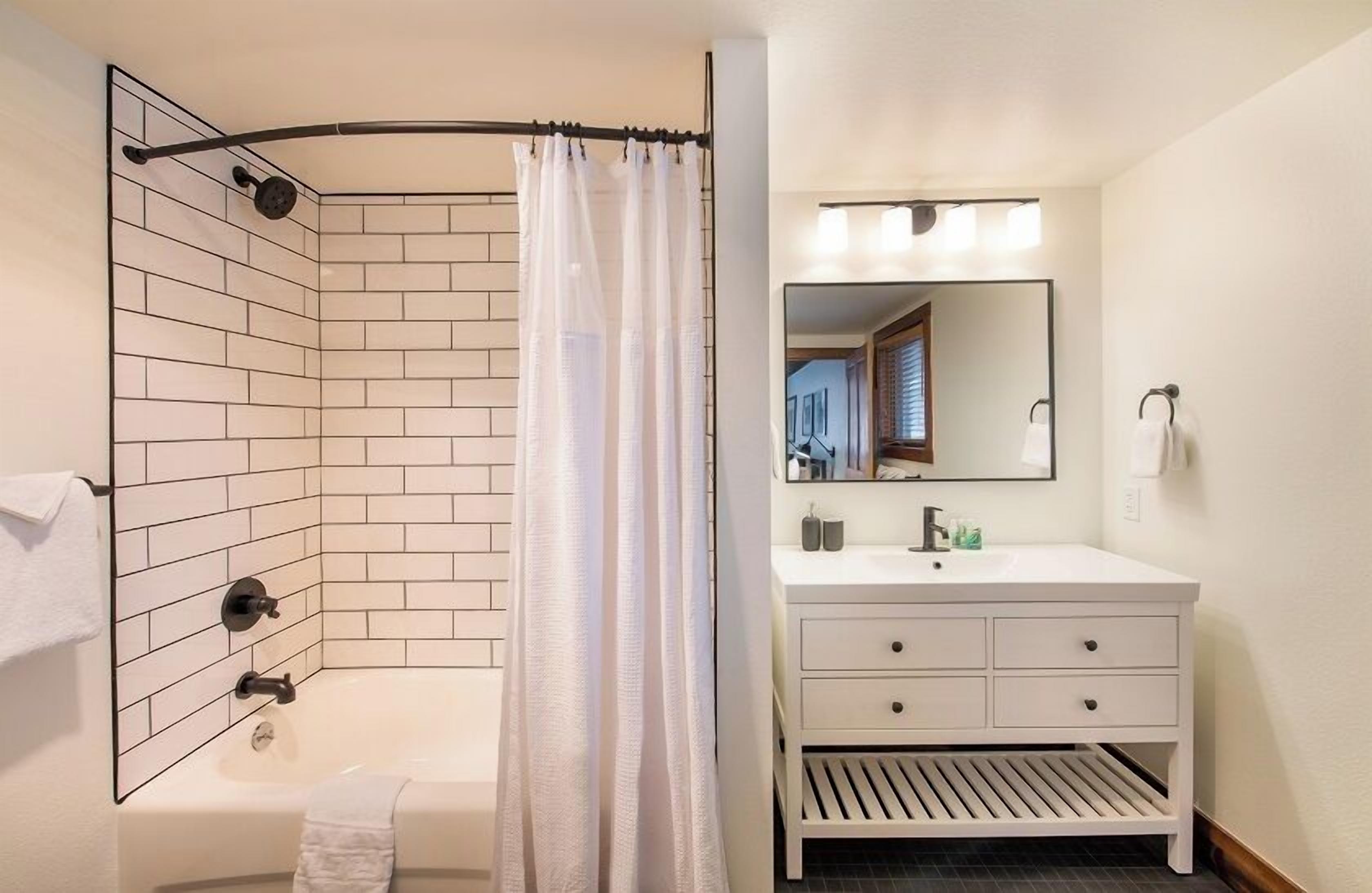 A bathroom with a shower, a sink, and a mirror.