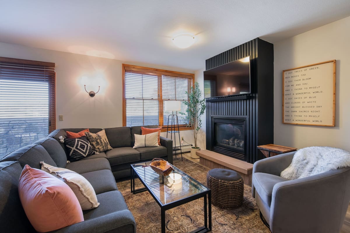 Una sala de estar con sofá, sillón, mesa de centro y chimenea.