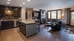 A modern kitchen with dark wood cabinets, a stone backsplash, and a central island. - Winter Park CO Condos - Zephyr Mountain Lodge (Winter Park)