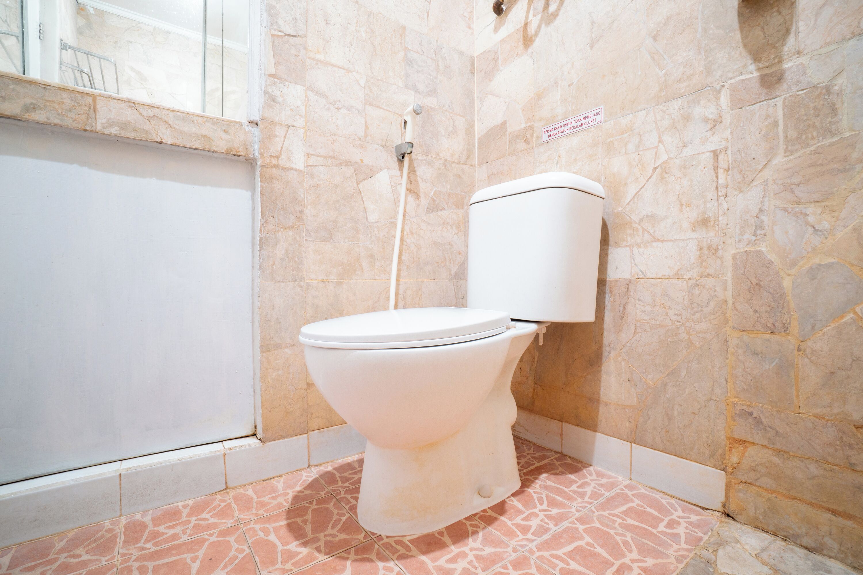 A bathroom with a toilet, a shower, and a tiled floor.