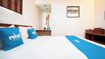 A hotel room with a bed, a nightstand, a mirror, and a framed picture on the wall.