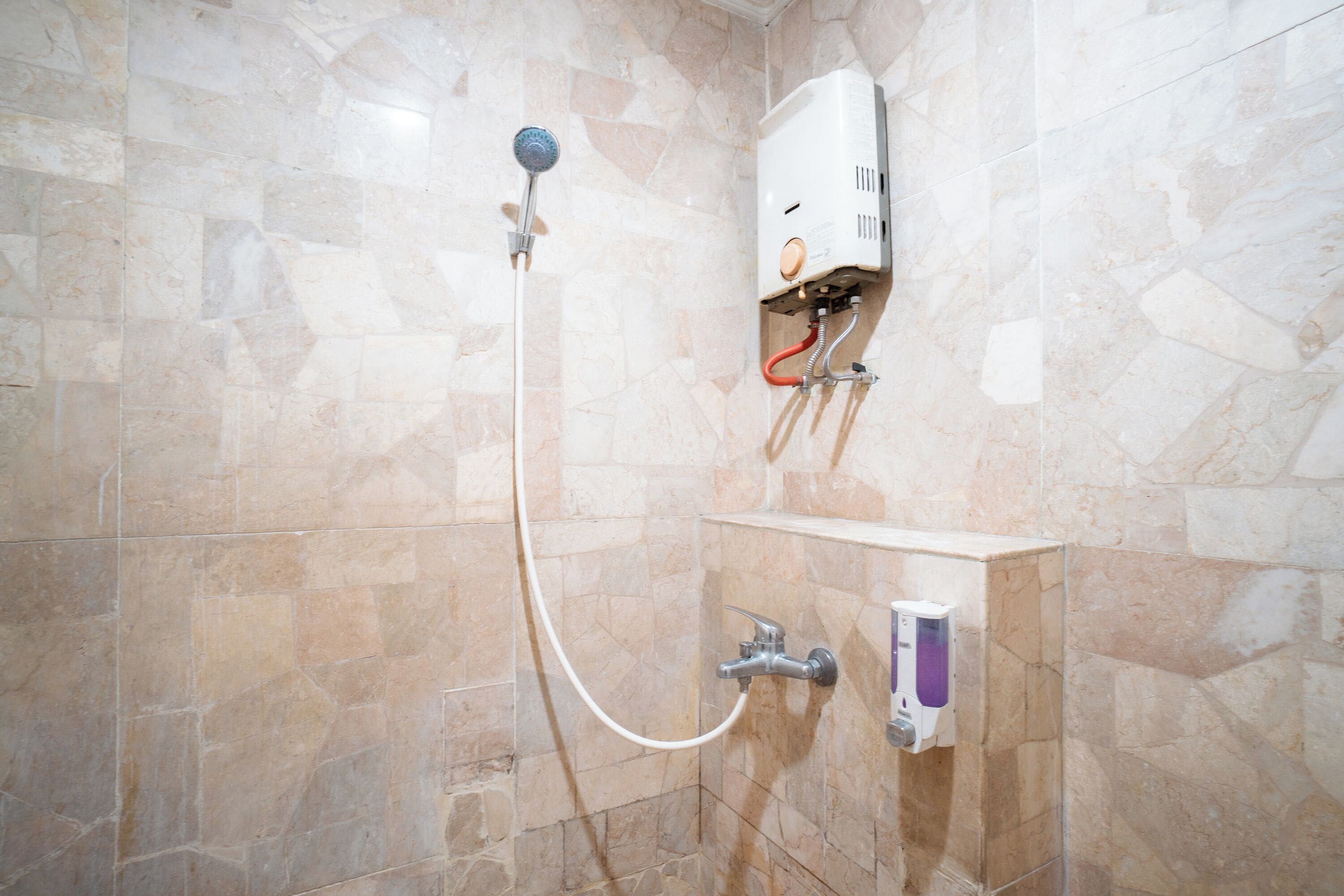Een badkamer met een douche, een wandradiator en een zeepdispenser.