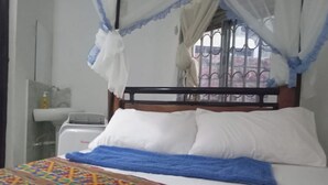 Uma cama com um cobertor estampado, almofadas brancas e um dossel.