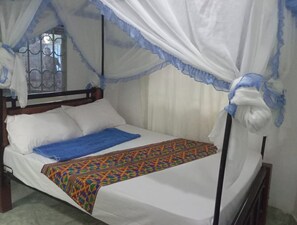 A bed with a canopy, white bedding, and a colorful blanket. - Naap Hotel & Guest House (Lodwar)