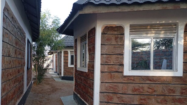 Uma fileira de casas com paredes de tijolo e telhados de cerâmica, uma passagem estreita e chão de terra.